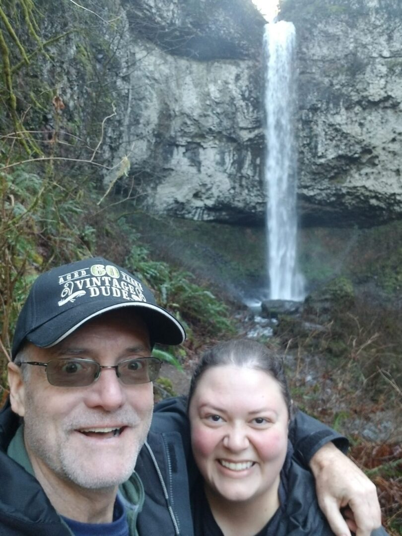 Happy couple taking selfie behind waterfall