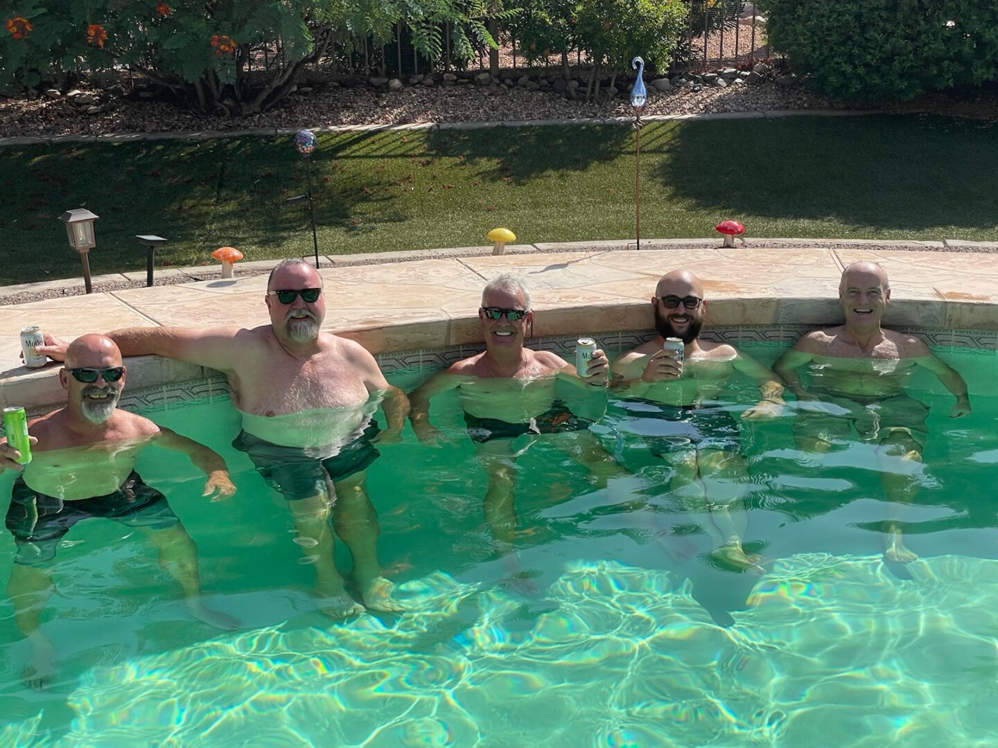 Senior Men holding drinks in swimming pool