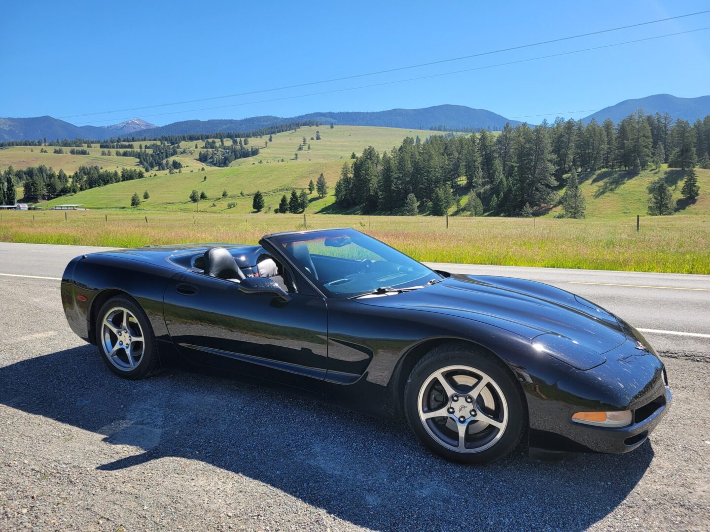 Black sport car on the road near the fields